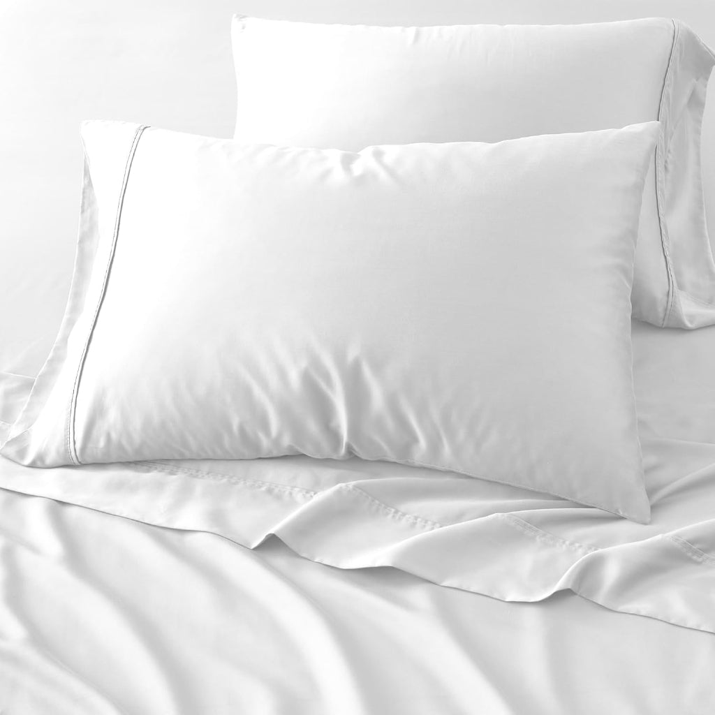 Two white pillows on a white bed