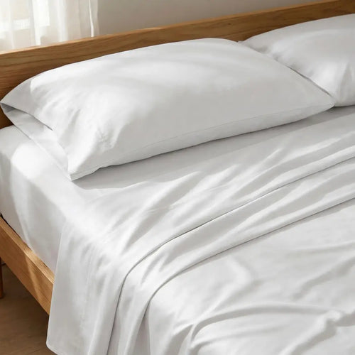 White bed sheets and two white pillows neatly arranged on a wooden bed frame.