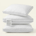 Three white pillows stacked on a light beige background with a label.