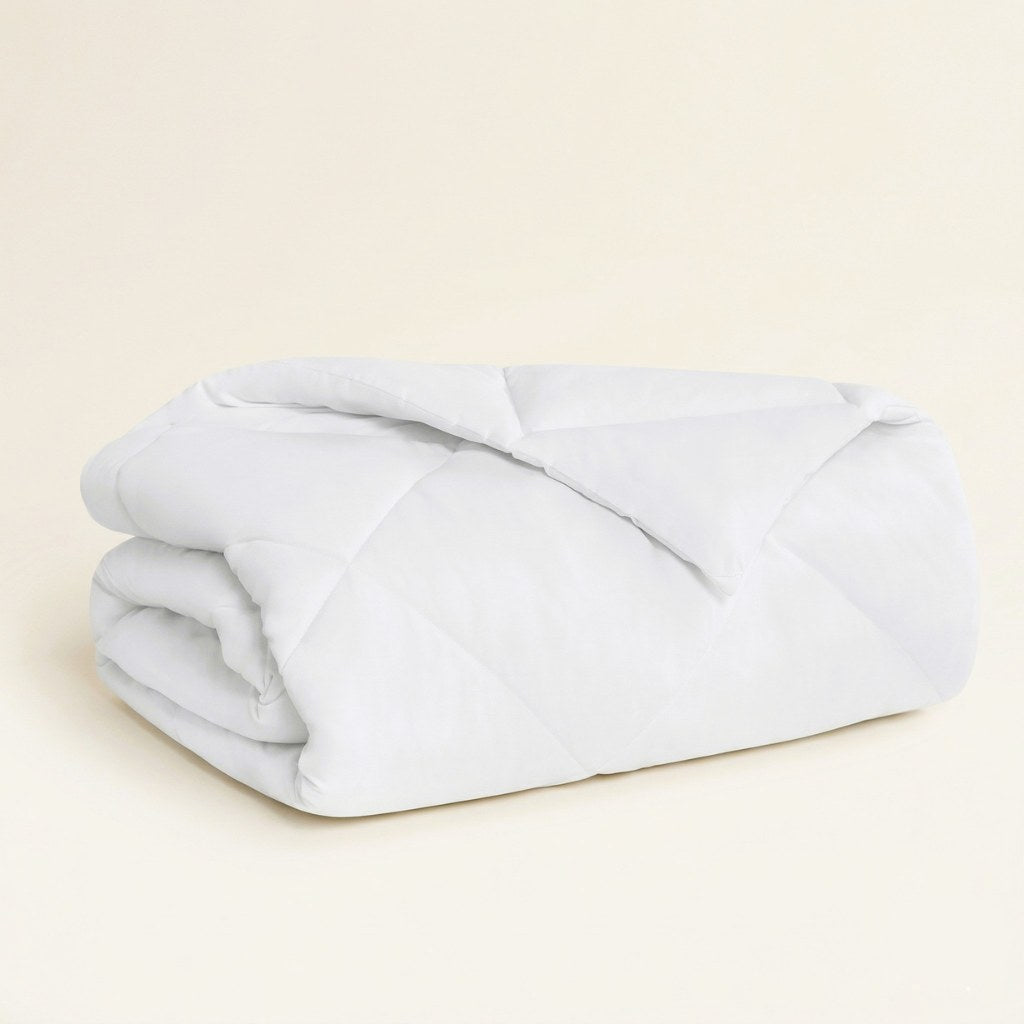 Folded light white comforter on a beige background