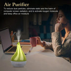 Woman sitting at a desk with a green air purifier, laptop, and pink mug.