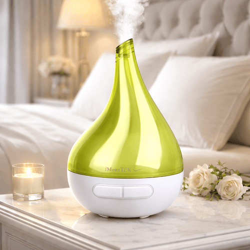 Green and white humidifier on a nightstand with a candle and flowers in the background