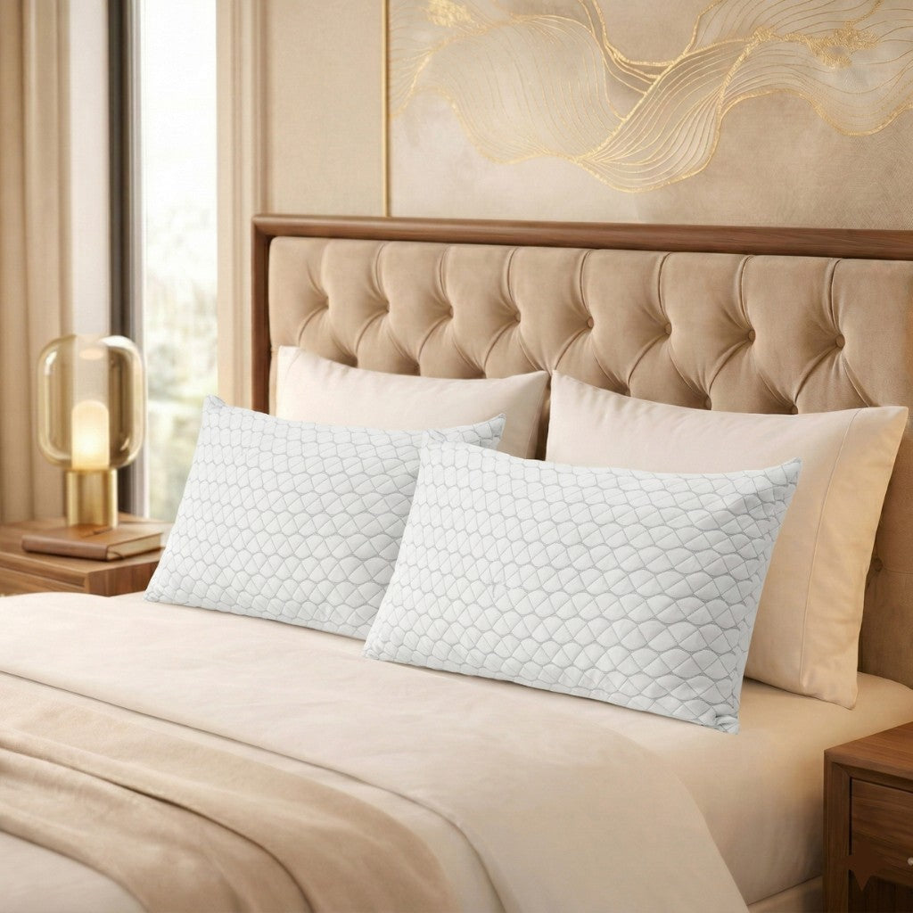 Decorative Adjustable pillows on a bed with a beige headboard and lamp in a bedroom setting.