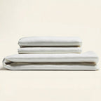 Stack of white folded bed sheets on a beige background