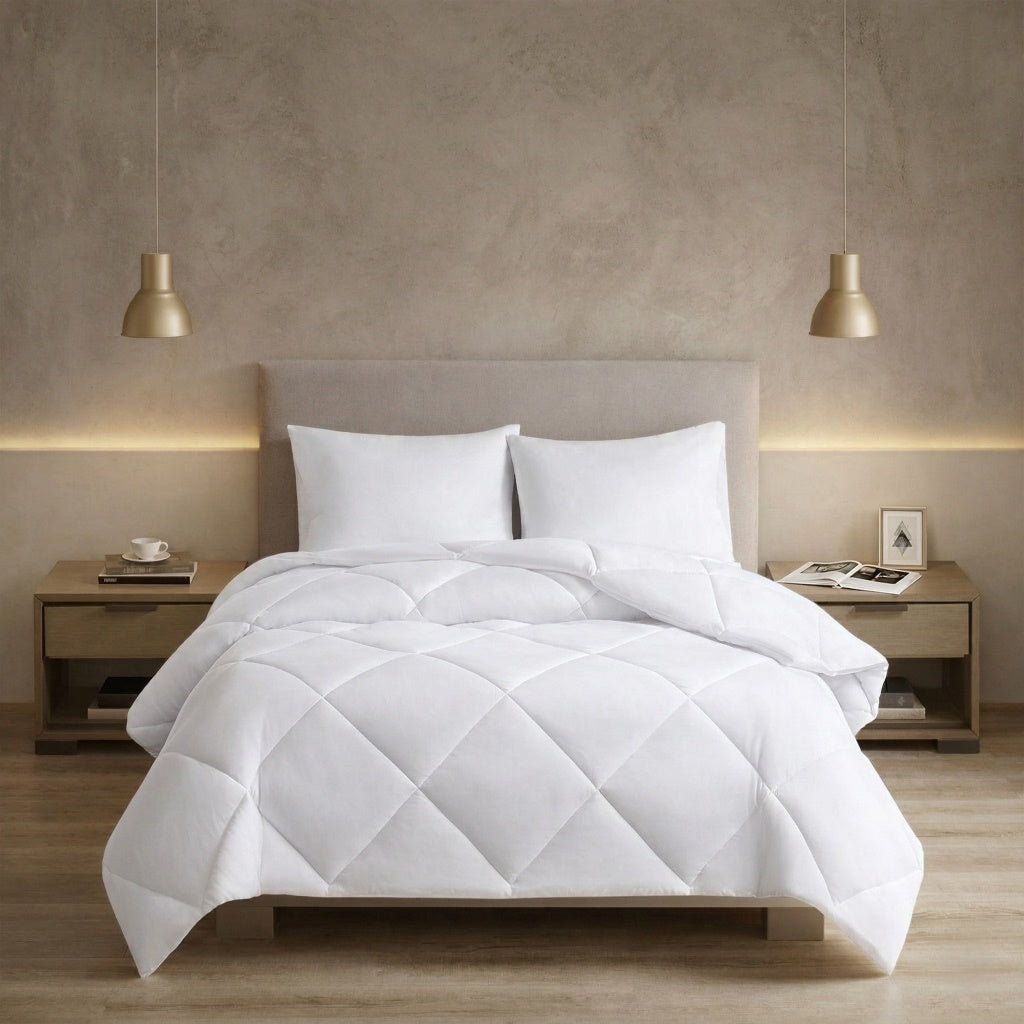 White quilted comforter on a bed in a bedroom setting with two nightstands and lamps. 