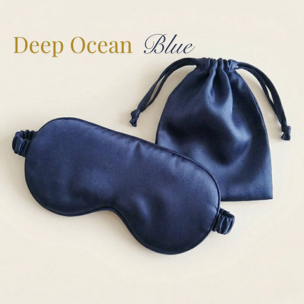 Navy blue satin eye mask with drawstring on a beige background, labeled 'Deep Ocean Blue'.